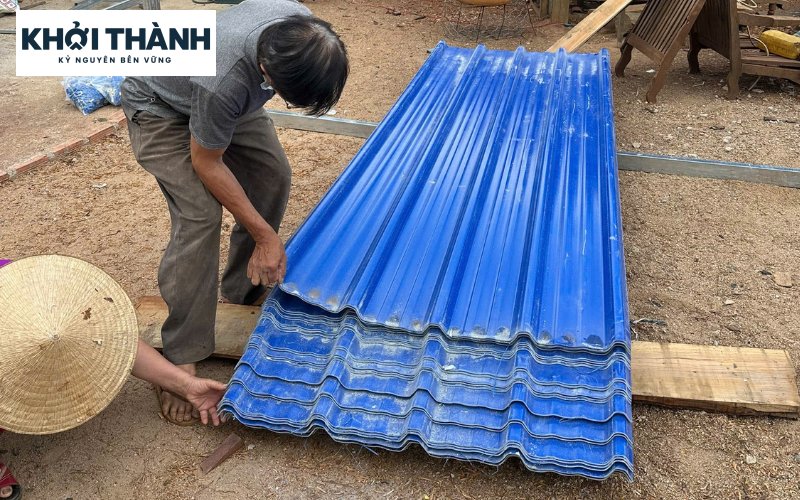 Người thợ sắp xếp các tấm lợp xanh dương trên hệ đỡ.